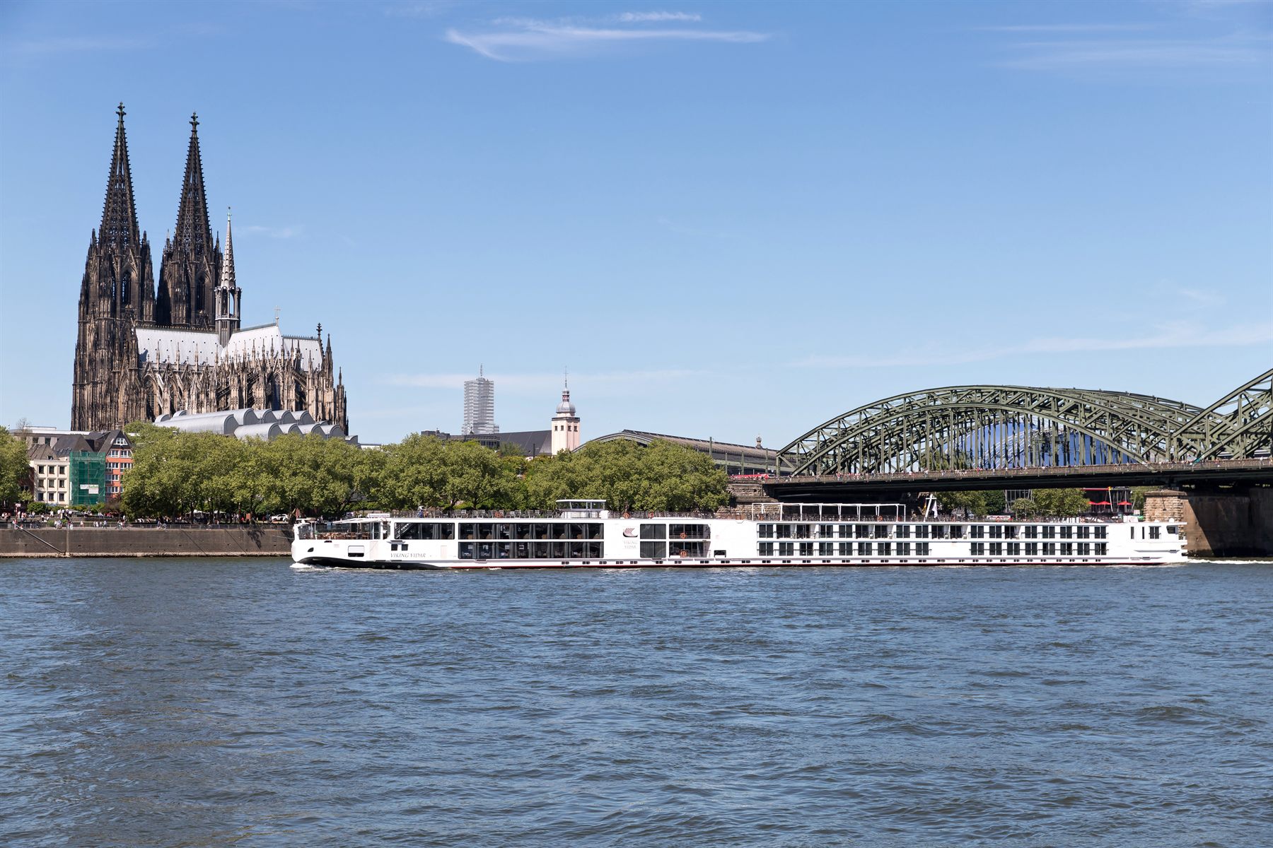 River cruise ship on the Rhine below Cologne Cathedral and the Hohenzollern Bridge