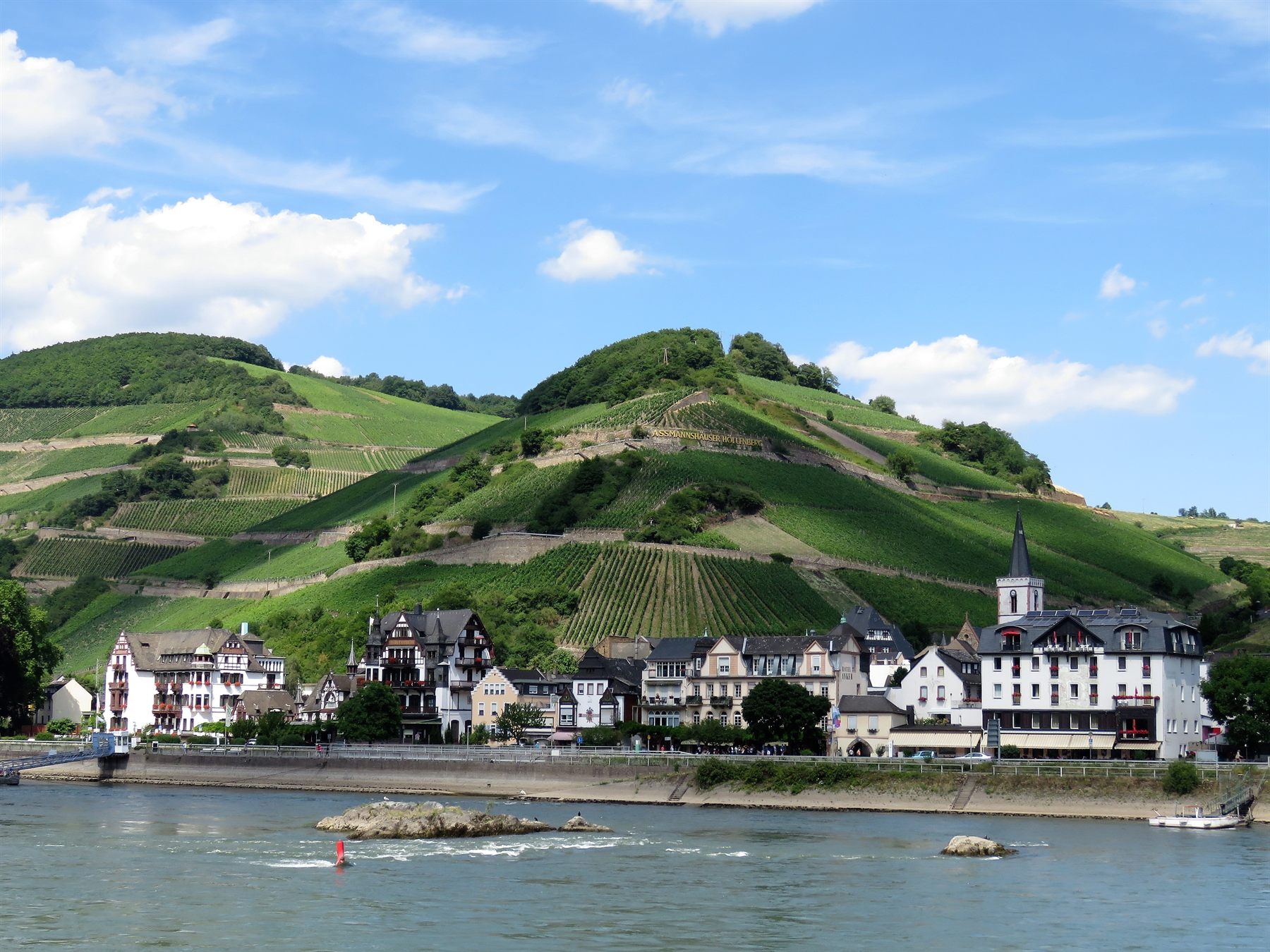 Riverside village of half-timbered houses below vineyard-covered hills